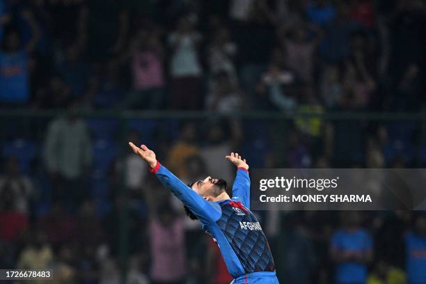 Afghanistan's Rashid Khan celebrates after taking the wicket of England's Mark Wood during the 2023 ICC Men's Cricket World Cup one-day international...