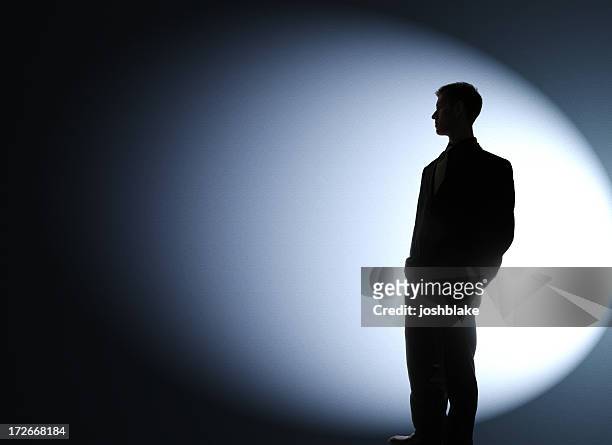 businessman silhouetted in a spotlight - spotlight person stock pictures, royalty-free photos & images