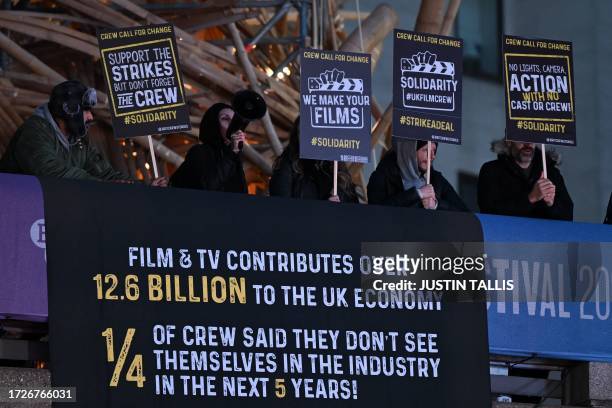 Demonstrators hold placards calling for change for the crews of UK TV and films productions, at the world Premiere of the film "The Kitchen" during...