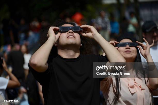 October 14 Mexico City, Mexico: A couple is seen observing the annular solar eclipse with special filter glasses for the sun at the National...