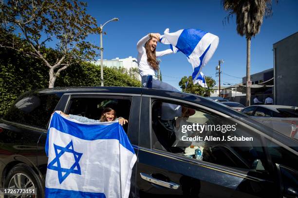 People fly Israeli flags from their car while watching thousands marching as the The Simon Wiesenthal Center, the Museum of Tolerance, the Jewish...