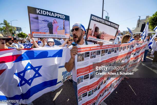 Boaz Hillel, center, of Woodland Hills, holds a banner of kidnapping victims by Hamas while joining thousands marching as the The Simon Wiesenthal...