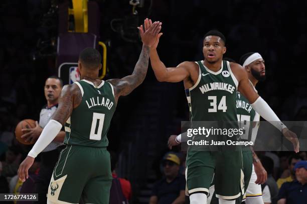 Damian Lillard high fives Giannis Antetokounmpo of the Milwaukee Bucks during the preseason game on October 15, 2023 at Crypto.Com Arena in Los...