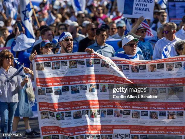 Boaz Hillel, left, of Woodland Hills, holds a banner of kidnapping victims by Hamas while joining thousands marching as the The Simon Wiesenthal...