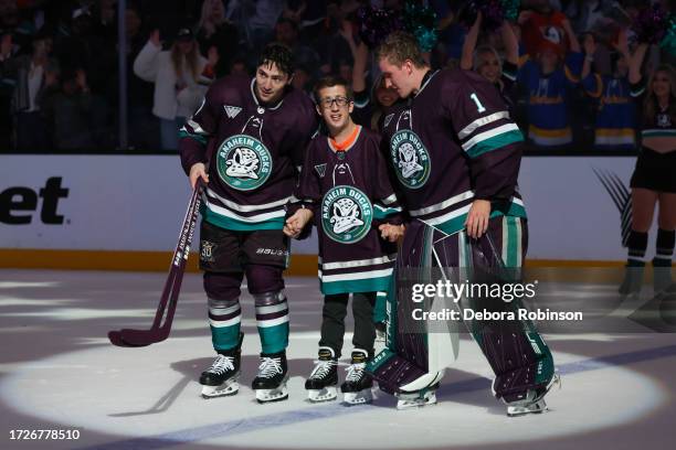 Frank Vatrano and Lukas Dostal of the Anaheim Ducks assist this year's 21st Duck, Trent Sullivan, following a 6-3 win against the Carolina Hurricanes...