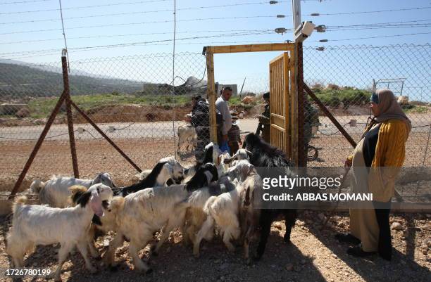 Israeli forces open a gate for Palestinian villagers from Bilin in the West Bank, as they prepare to cross Israel's separation barrier to go work in...