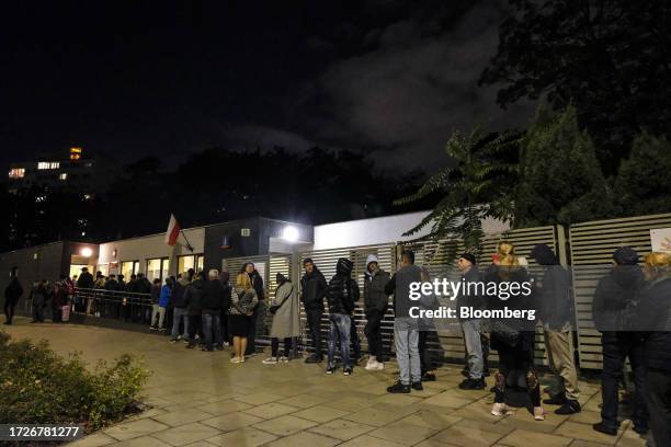 Residents queue to cast their votes at the election commission during the general election in Warsaw, Poland, on Sunday, Oct. 15, 2023. Poland's...