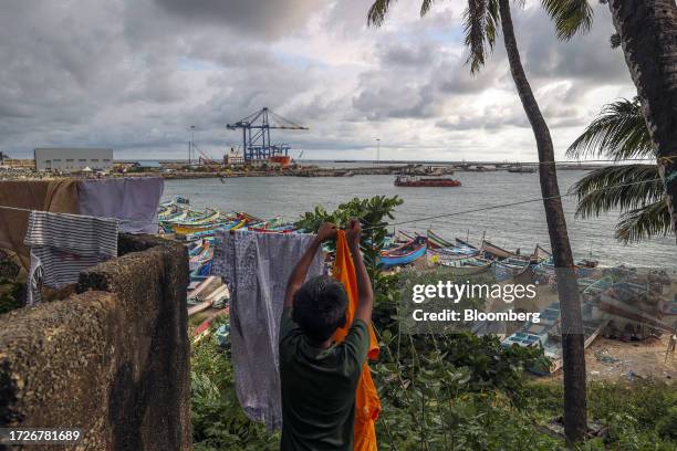 Resident hangs clothes to dry at Vizhinjam Village as a gantry crane and the Zhen Hua 15 heavy load cargo carrier at the Vizhinjam transshipment...