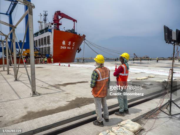 Workers in front of the Zhen Hua 15 heavy load cargo carrier at the Vizhinjam transshipment container port, developed by Adani Ports and Special...