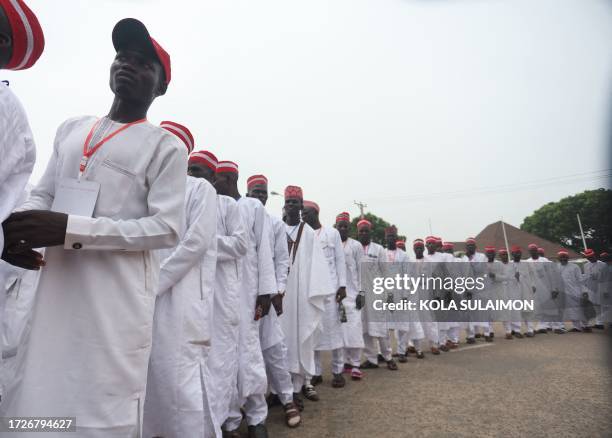 Grooms dressed in white robes and red caps walk on the street of Kano to attend a wedding reception at the Kano state governor's office after taking...