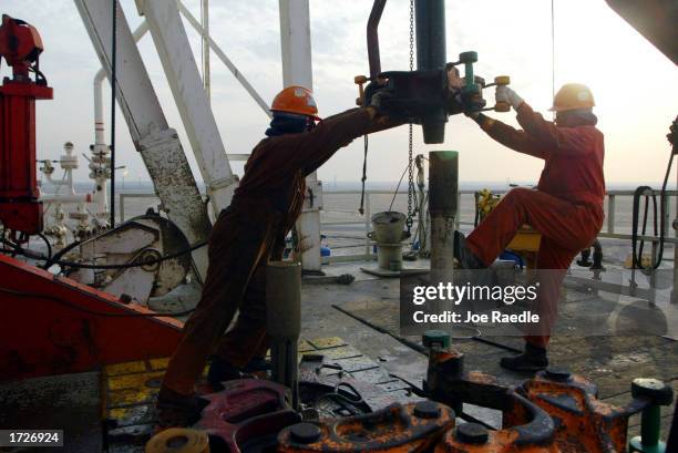 Oil rig workers work on the ChevronTexaco drilling platform January 15, 2003 near the Saudi Arabian border, Kuwait. Kuwait produces 10% of the worlds...