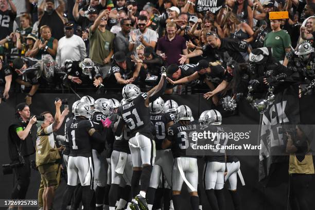 Robert Spillane of the Las Vegas Raiders celebrates with teammates and fans after intercepting the ball during the second quarter against the Green...