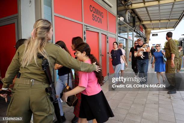 An Israeli soldier ushers people to a bomb shelter during a rocket attack in the southern Israeli city of Ashdod, on October 16, 2023. The death toll...