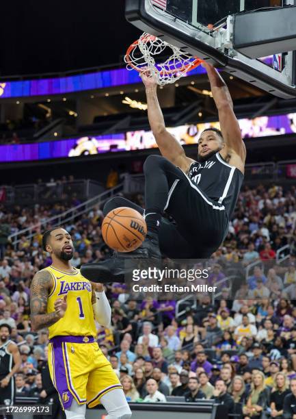 Ben Simmons of the Brooklyn Nets dunks ahead of D'Angelo Russell of the Los Angeles Lakers in the second quarter of their preseason game at T-Mobile...