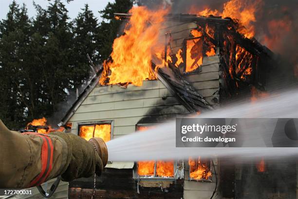 close-up of firemans hose shooting water at house fire - burning stock pictures, royalty-free photos & images