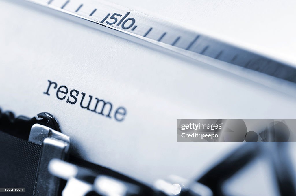 White paper in a typewriter with the word resume typed.