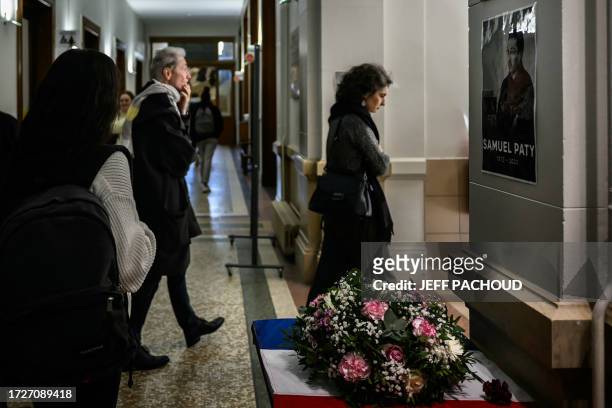 Students and teachers pass by a portrait of late French teacher Samuel Paty in a high school in Lyon on October 16, 2023 during a tribute to late...