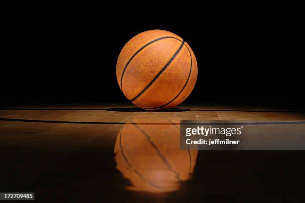 basketball lying on shiny court against black background - basketball floor stockfoto's en -beelden
