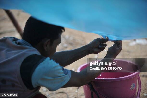 Villager collects water from the rain at Sabeugunggung village in the Metawai islands, West Sumatra, on October 31, 2010 six days after a...