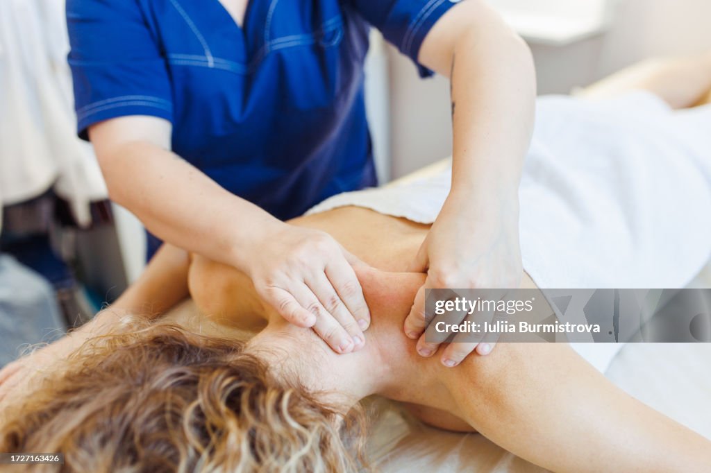 Slender female client receives rejuvenating sports massage targeting shoulder muscles