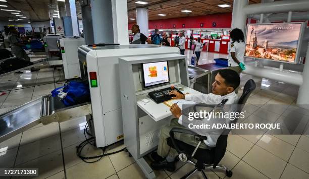 Customs officer checks passengers' luggage on a scanner at Havana's Jose Marti airport on October 12, 2023.