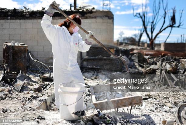 Daughter uses a shovel as she searches for family items in the rubble of her mother's wildfire destroyed home on October 09, 2023 in Lahaina, Hawaii....