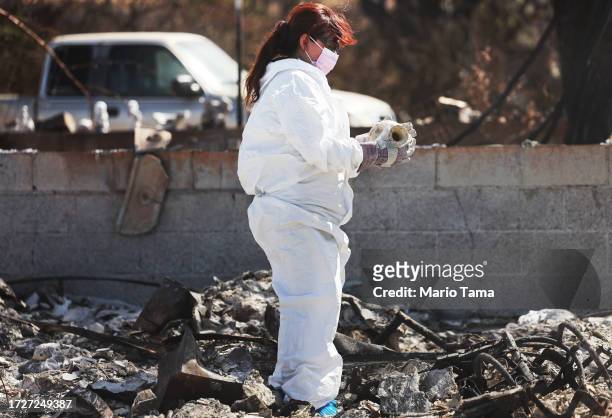 Daughter looks at a vase she found while searching for family items in the rubble of her mother's wildfire destroyed home on October 09, 2023 in...