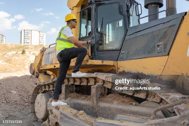 trabajador de la construcción entrando en la cabina de una excavadora en el sitio de construcción - mina de superficie fotografías e imágenes de stock