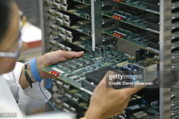 An Israeli technician slides a completed Micro SDM-1 card into a trolley at an ECI Telecom high-tech plant January 15, 2003 in Petah Tikva which is...