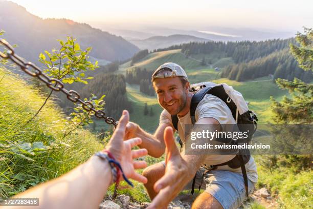 partner offers man a hand up, hiking the alps - trust exercise stock pictures, royalty-free photos & images