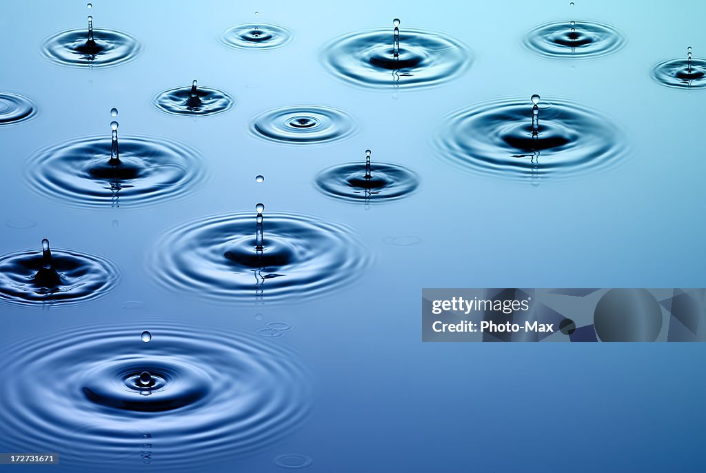 Close-up of falling raindrops and associated ripples