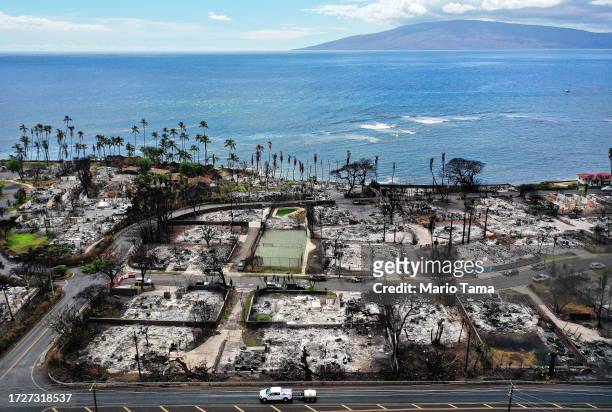 In an aerial view, a recovery vehicle drives past burned structures and cars two months after a devastating wildfire on October 09, 2023 in Lahaina,...