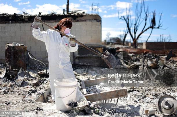 Daughter uses a shovel as she searches for family items in the rubble of her mother's wildfire destroyed home on October 09, 2023 in Lahaina, Hawaii....