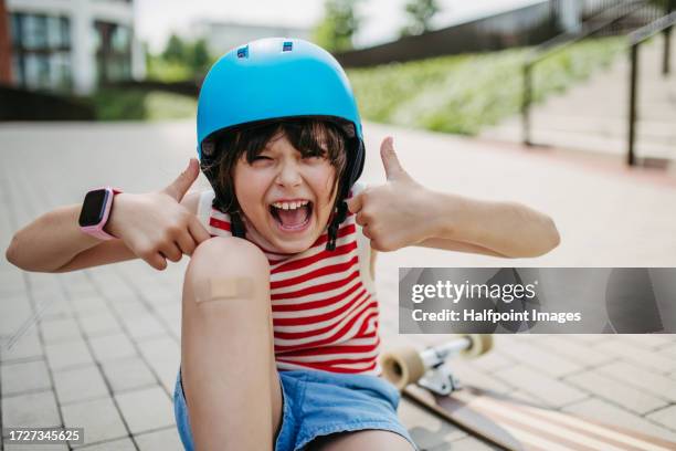 portrait of a young girl with a helmet on, skateboarding outdoors. - medische artikelen stockfoto's en -beelden