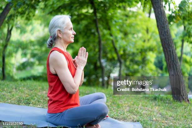 senior latin woman doing yoga training exercise wearing red sportswear. old lady with grey hair making fitness relaxation exercise. - boa postura imagens e fotografias de stock