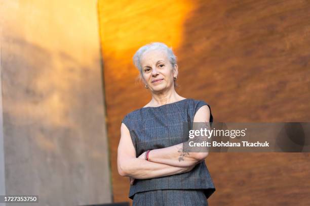 portrait of senior hispanic business lady with grey hair using on brown background. old business woman posing for camera - lady grey background bildbanksfoton och bilder
