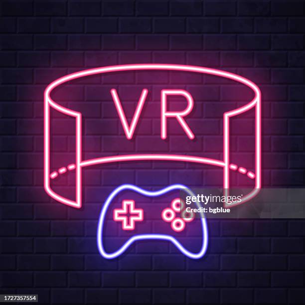 vr game - virtual reality game. glowing neon icon on brick wall background - controller joystick stock illustrations