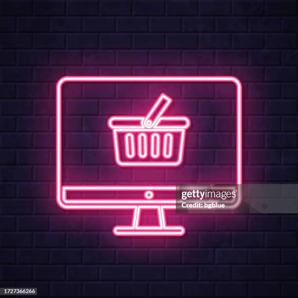desktop computer with shopping basket. glowing neon icon on brick wall background - plasma bag stock illustrations