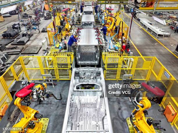 Robotic arms weld parts of electric express delivery vehicles on the assembly line at a factory on October 9, 2023 in Ganzhou, Jiangxi Province of...