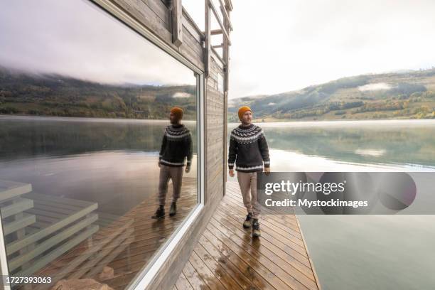 young man relaxing outside of a floating sauna, he enjoys the freshness of the outdoors - autumn norway stock pictures, royalty-free photos & images