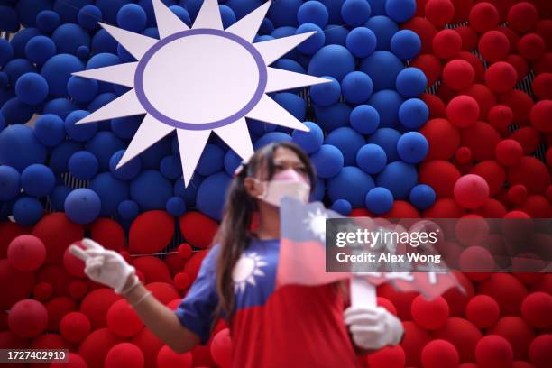 Woman poses for photos in front of a Taiwanese flag made with balloons during a fair to mark the National Day at Zhongzhen New Village Cultural Park...