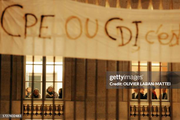 People stand in front of the windows of the College de France, an elite research institution in the capital's Latin Quarter, after a demonstration...