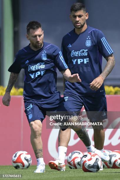 Argentina's forward Lionel Messi passes the ball next to defender Cristian Romero during a training session in Ezeiza, Buenos Aires on October 16...