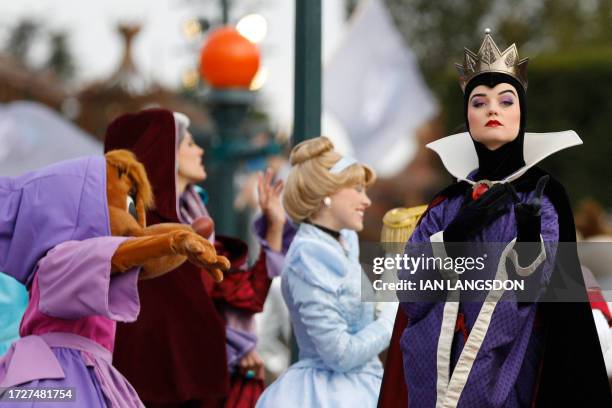 Disney cast members Cinderella , and Evil Queen , take part in a parade during a ceremony marking the 100th anniversary of the Walt Disney Company,...