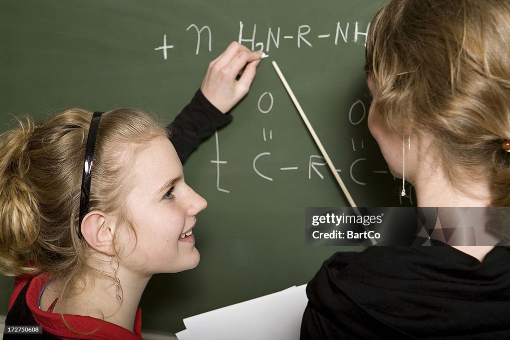 Young girl is learning chemistry, teacher helps