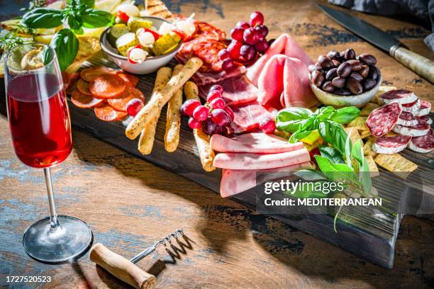 mediterranean appeticer wooden board, cold cuts meat charcuterie and cheese with red wine - italian food and wine stock pictures, royalty-free photos & images