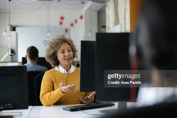 glückliche frau, die mit jemandem im it-support-center spricht. - freisprechanlage stock-fotos und bilder