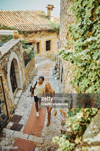 glückliches millennial-paar, das im urlaub das historische dorf eze in südfrankreich erkundet. - eze village stock-fotos und bilder