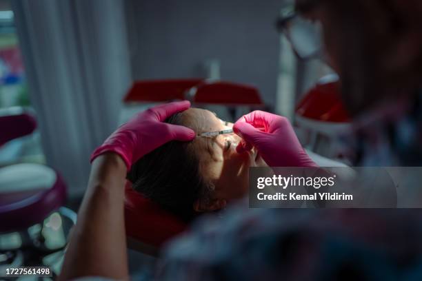 mid adult woman is getting a rejuvenating facial injections at beauty clinic - plastic surgery stockfoto's en -beelden