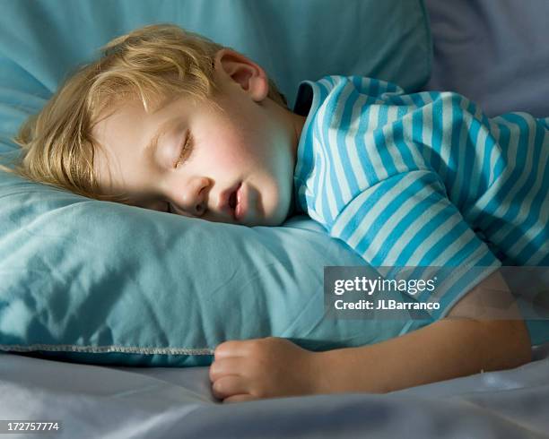 young boy in blue, peacefully sleeping on a blue pillow - sleeping toddler bed stock pictures, royalty-free photos & images